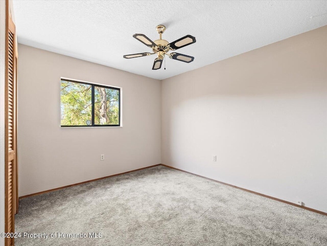 carpeted spare room featuring ceiling fan and a textured ceiling