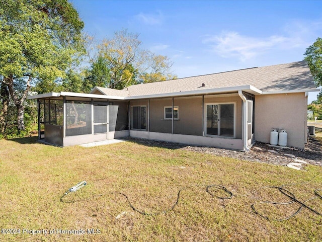 rear view of house with central air condition unit, a sunroom, and a yard