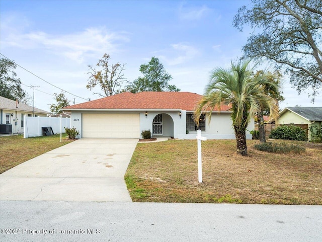 ranch-style home with central AC unit, a garage, and a front lawn