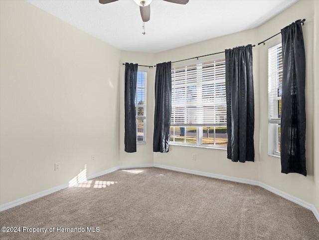 carpeted spare room featuring ceiling fan and a healthy amount of sunlight