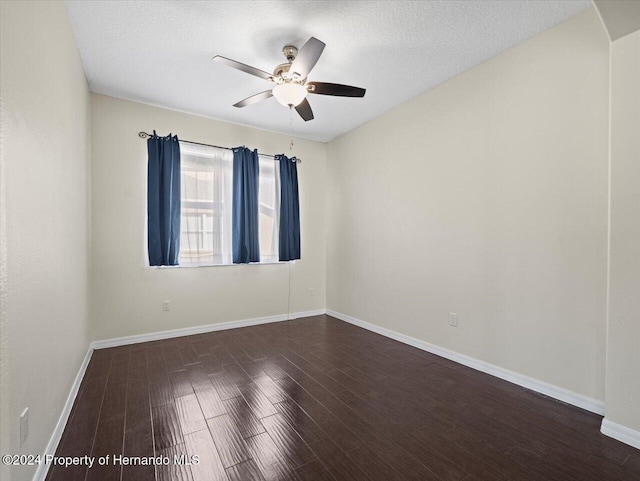 spare room with a textured ceiling, ceiling fan, and dark wood-type flooring