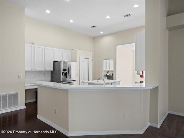 kitchen featuring kitchen peninsula, stainless steel fridge, white cabinets, and dark hardwood / wood-style floors