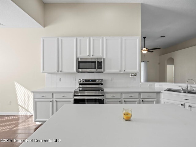 kitchen with sink, decorative backsplash, appliances with stainless steel finishes, white cabinetry, and wood-type flooring