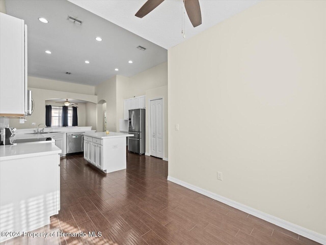 kitchen featuring appliances with stainless steel finishes, dark wood-type flooring, sink, white cabinets, and a center island