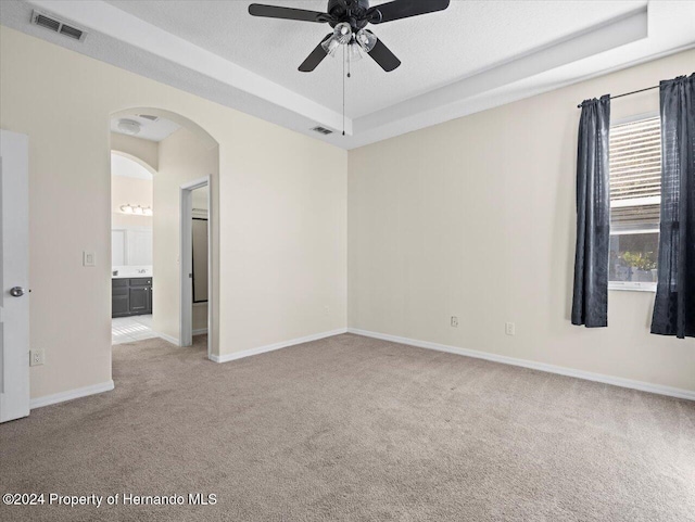 carpeted spare room featuring a textured ceiling, a raised ceiling, and ceiling fan