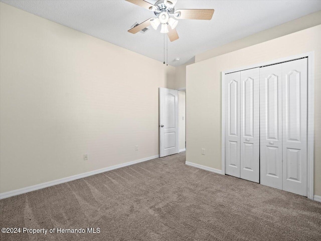 unfurnished bedroom featuring carpet flooring, ceiling fan, and a closet