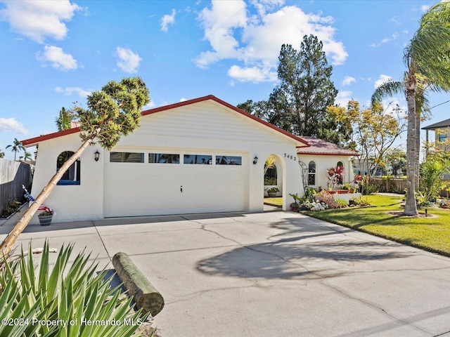 mediterranean / spanish house with a garage and a front lawn