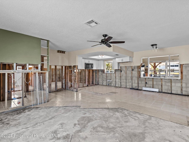 interior space with ceiling fan, light tile patterned flooring, and a textured ceiling