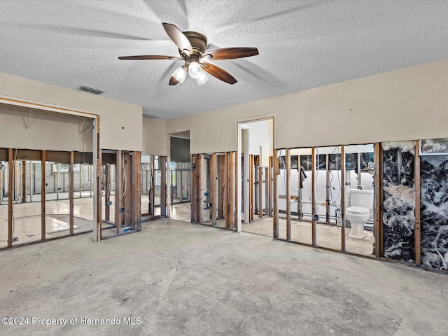 empty room with ceiling fan, concrete flooring, and a textured ceiling