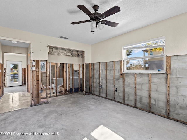 unfurnished room featuring a textured ceiling, ceiling fan, and concrete floors