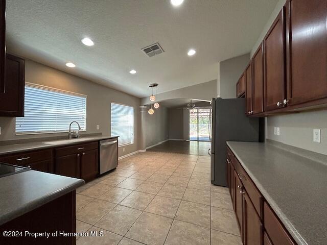 kitchen featuring stainless steel dishwasher, ceiling fan, sink, pendant lighting, and light tile patterned floors