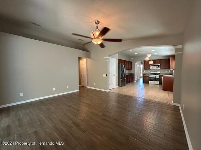 unfurnished living room with ceiling fan, dark hardwood / wood-style flooring, and sink