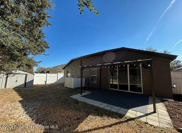 back of house featuring a patio and a storage unit