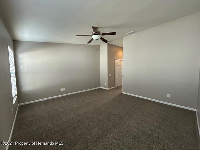 spare room with ceiling fan and dark carpet