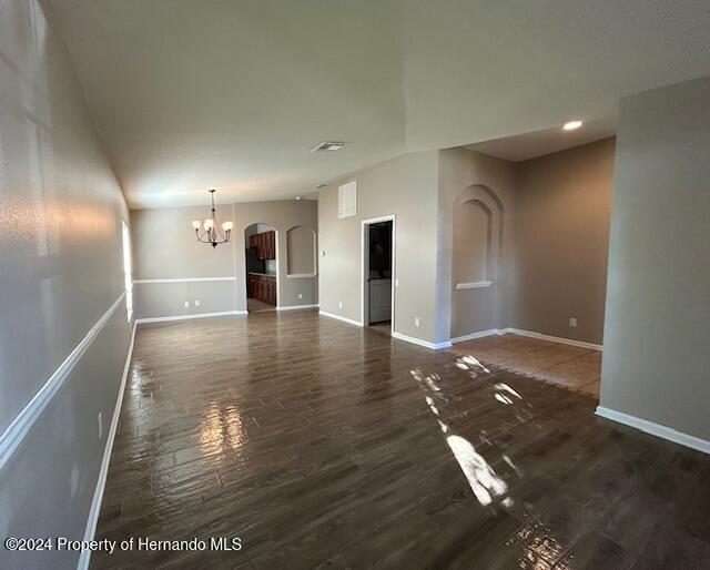 unfurnished living room with a chandelier and dark hardwood / wood-style flooring