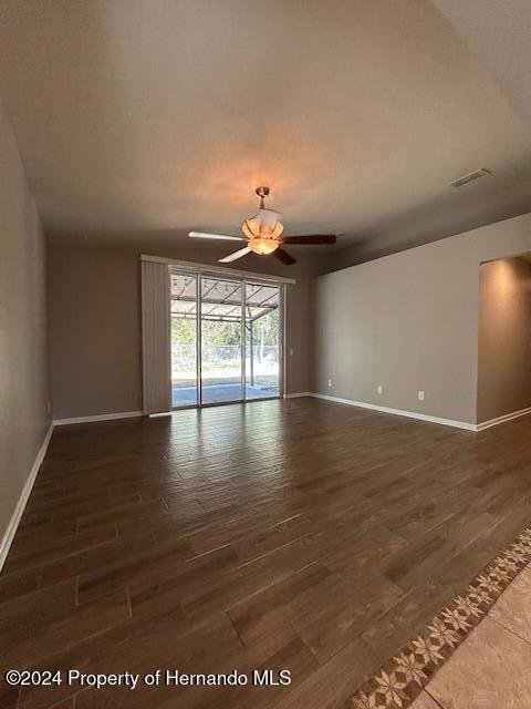 empty room with ceiling fan and dark hardwood / wood-style flooring