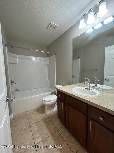 full bathroom with tile patterned floors, bathing tub / shower combination, a textured ceiling, toilet, and vanity