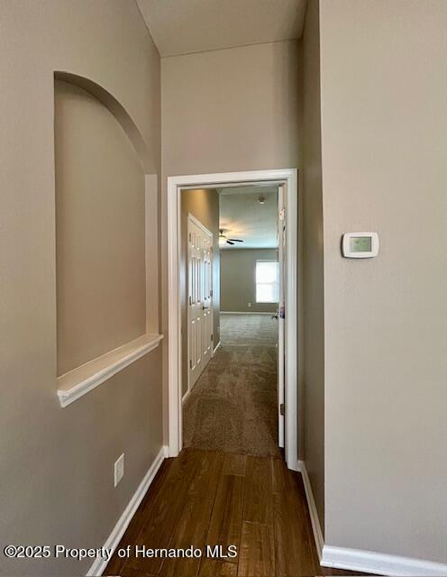 corridor featuring dark wood-style floors and baseboards