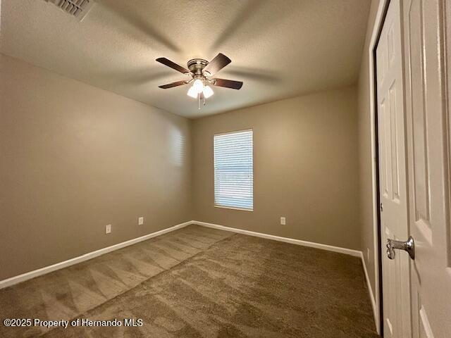 interior space featuring carpet floors, visible vents, a textured ceiling, and baseboards