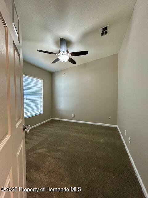 spare room with carpet flooring, ceiling fan, visible vents, and baseboards