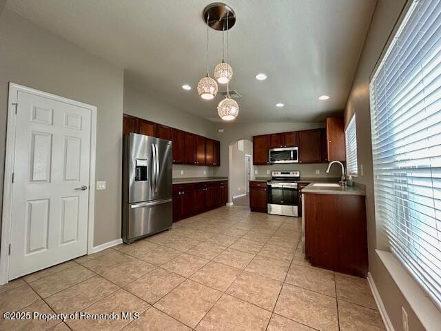 kitchen with stainless steel appliances, light countertops, light tile patterned flooring, and a sink