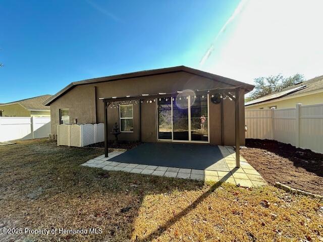 rear view of property featuring a yard, a patio area, a fenced backyard, and stucco siding