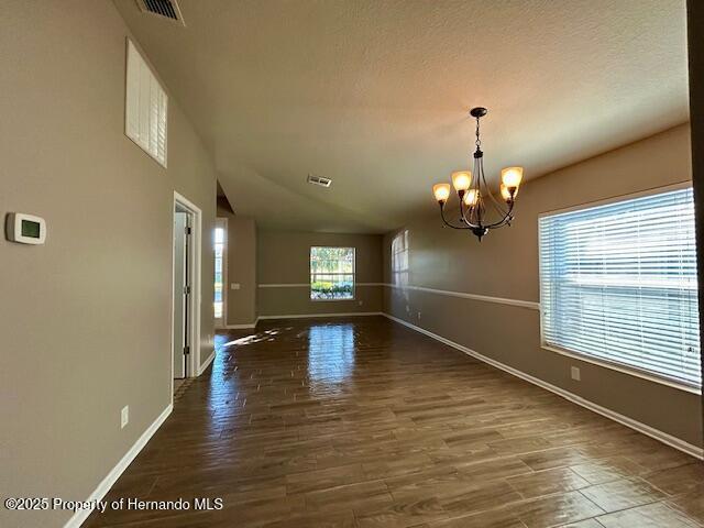 interior space with a chandelier, visible vents, baseboards, and wood finished floors