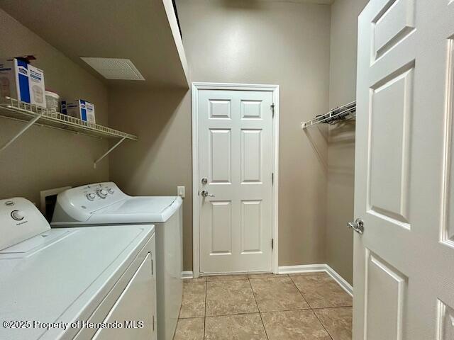 laundry area with light tile patterned floors, laundry area, separate washer and dryer, and baseboards