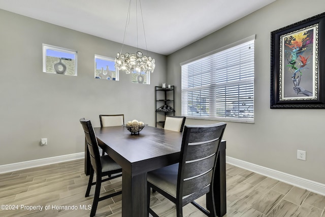 dining area with light wood-type flooring and an inviting chandelier