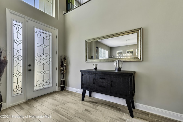 entrance foyer with a chandelier, a towering ceiling, and light hardwood / wood-style floors