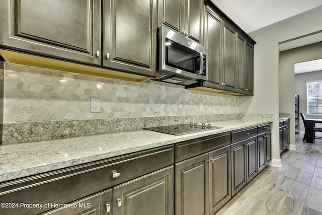 kitchen with light stone countertops, dark brown cabinetry, and black electric cooktop