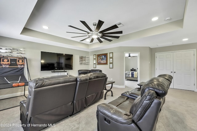 carpeted living room with a tray ceiling and ceiling fan