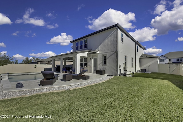 rear view of property featuring a yard, an outdoor living space, cooling unit, a fenced in pool, and a patio