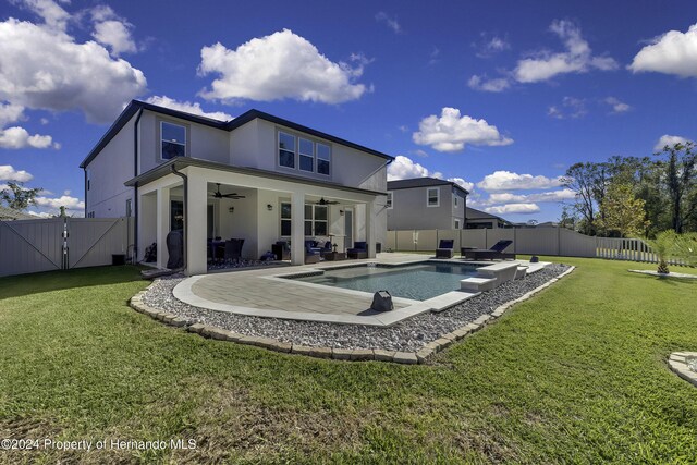 back of house with a lawn, ceiling fan, a fenced in pool, and a patio