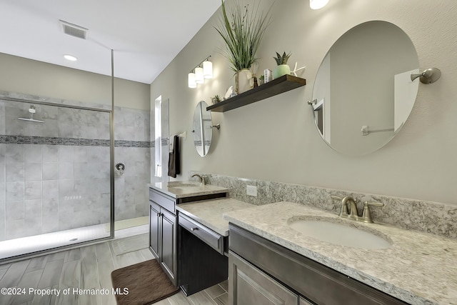 bathroom with tiled shower and vanity