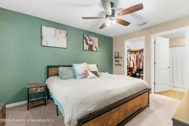 bedroom with a walk in closet, ceiling fan, a closet, and light wood-type flooring