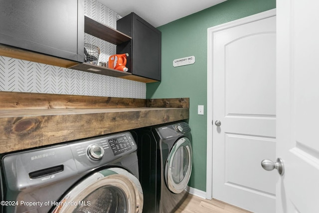 washroom with cabinets, washing machine and dryer, and light hardwood / wood-style flooring