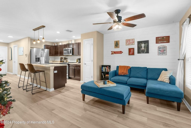 living room featuring ceiling fan and light hardwood / wood-style floors