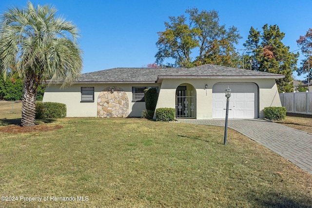 ranch-style house featuring a garage and a front lawn