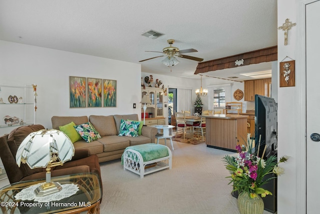 living room with ceiling fan with notable chandelier, light colored carpet, and a textured ceiling