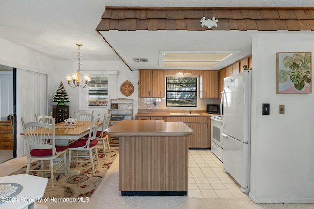 kitchen featuring a center island, white appliances, sink, hanging light fixtures, and a chandelier