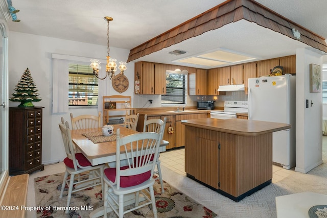 kitchen featuring light wood-type flooring, tasteful backsplash, white appliances, a notable chandelier, and a kitchen island