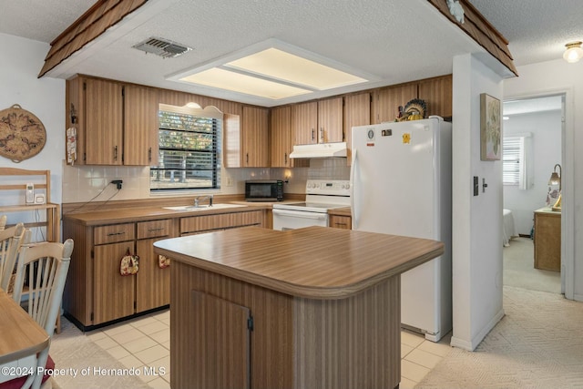 kitchen with a textured ceiling, tasteful backsplash, a kitchen island, and white appliances