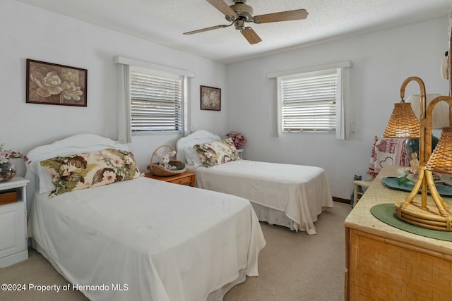 bedroom with ceiling fan, light carpet, and a textured ceiling