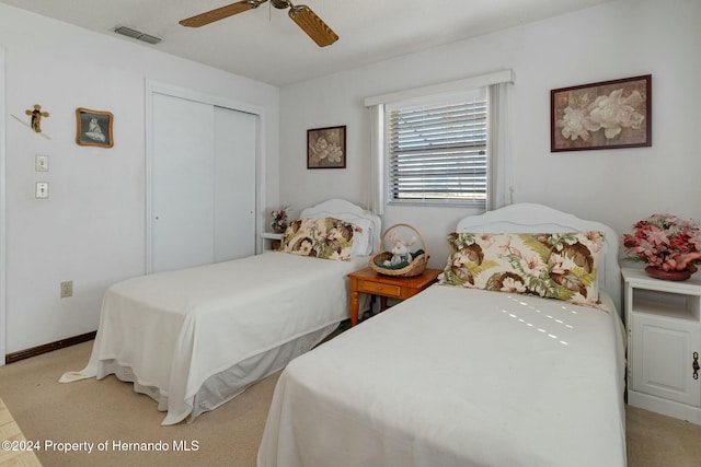 carpeted bedroom with ceiling fan and a closet