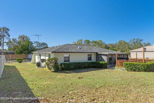 back of property with a lawn and central AC