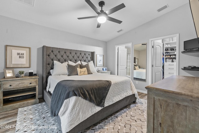 bedroom featuring a walk in closet, ceiling fan, wood-type flooring, and lofted ceiling