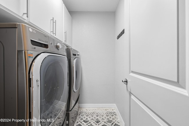 washroom with washer and dryer, tile patterned flooring, and cabinets