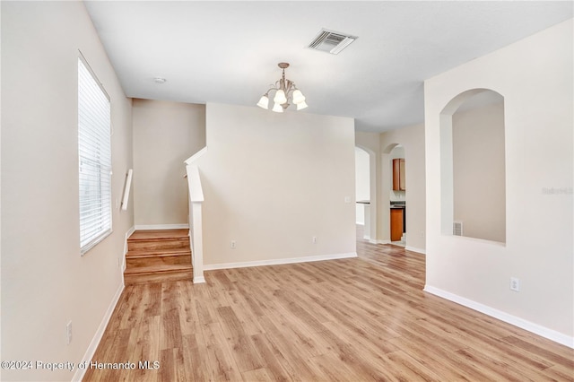 empty room with light hardwood / wood-style floors and an inviting chandelier