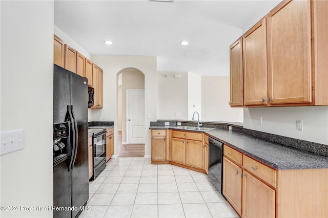 kitchen with kitchen peninsula, light tile patterned floors, sink, and black appliances